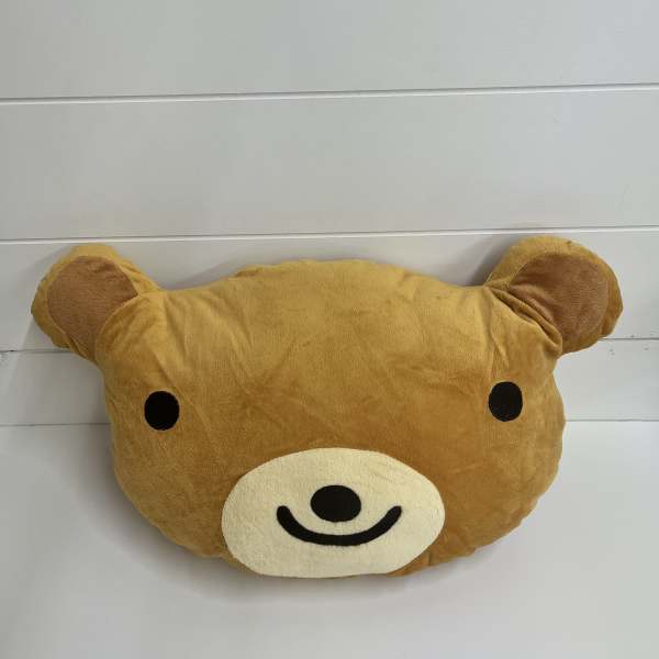 Brown teddy bear face plush pillow with black eyes and a smiling muzzle