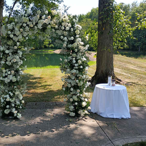 White floral arch outdoors beside a small table