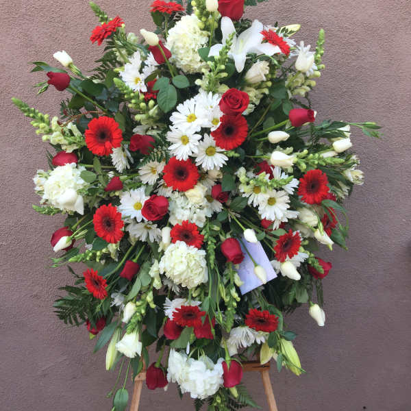 Large standing spray of red, white, and green flowers on an easel