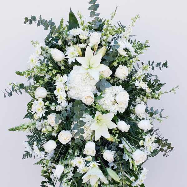 Large white floral standing spray with lilies, roses, and daisies