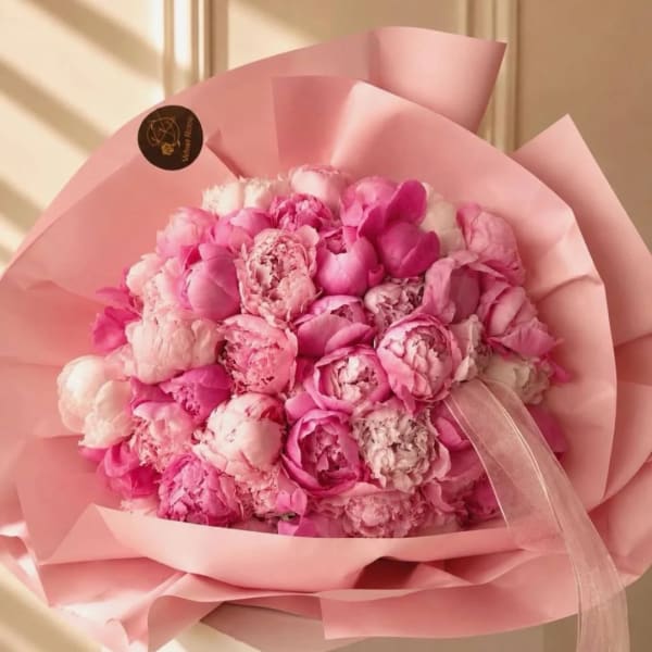 Pink bouquet of peonies wrapped in pale pink paper with a ribbon