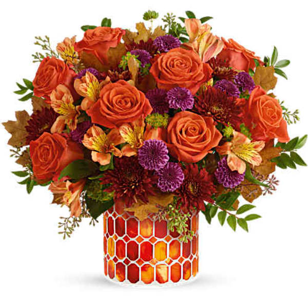 Orange roses and purple flowers in a patterned glass vase