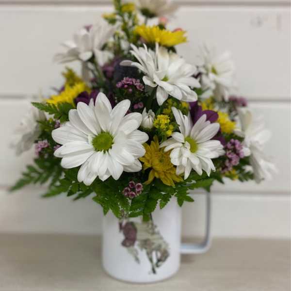 White and yellow daisy bouquet in a white mug