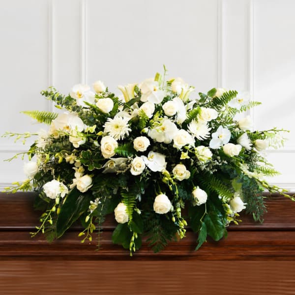 White floral arrangement with roses, orchids, and lilies in a low design