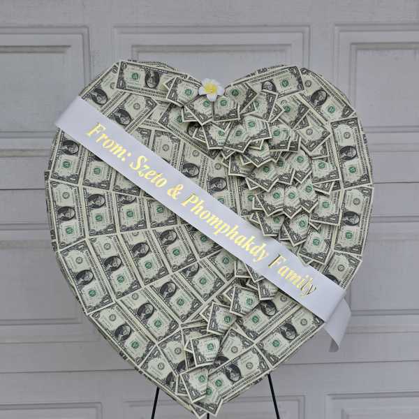 Heart-shaped money display with a white ribbon and small flower accent