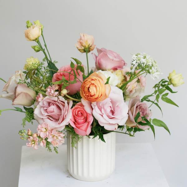 Pink and peach roses arranged in a white vase