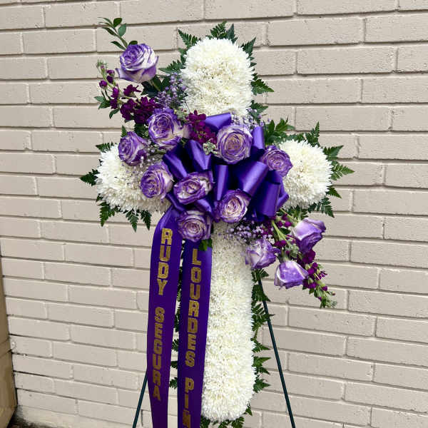 Purple and white funeral spray on a stand with ribbons