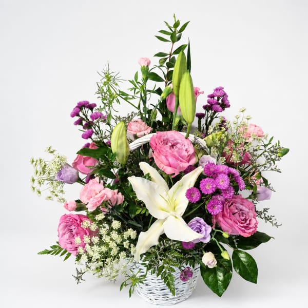 Pink and white mixed flower arrangement in a white basket