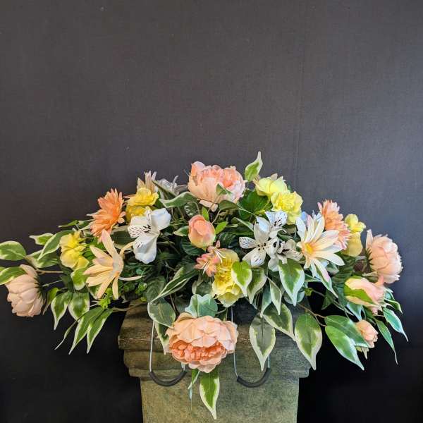 Peach and yellow floral arrangement in a stone urn