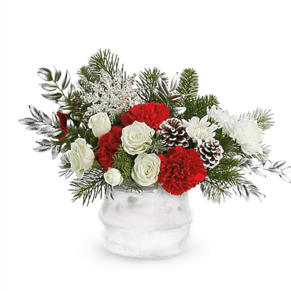 Red and white floral arrangement in a white vase with pinecones