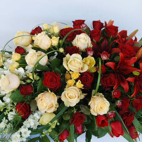 Red and cream roses with red lilies in a large floral spray