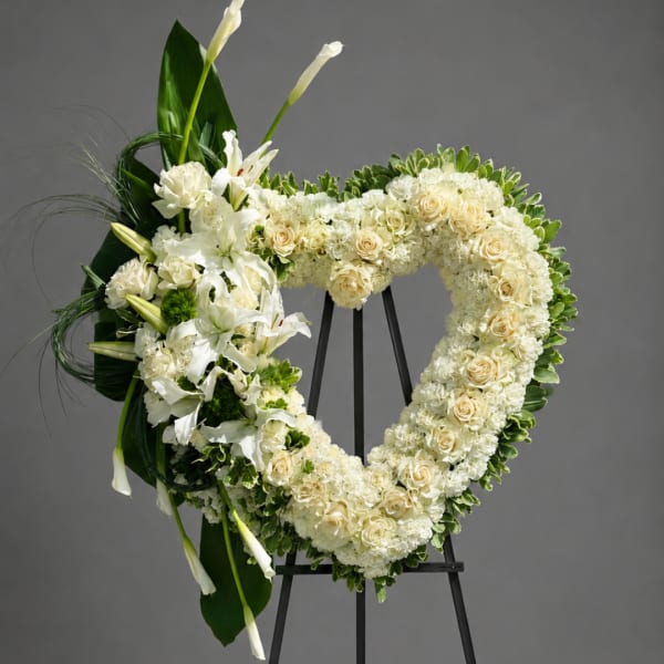 Heart-shaped white floral wreath on a black easel