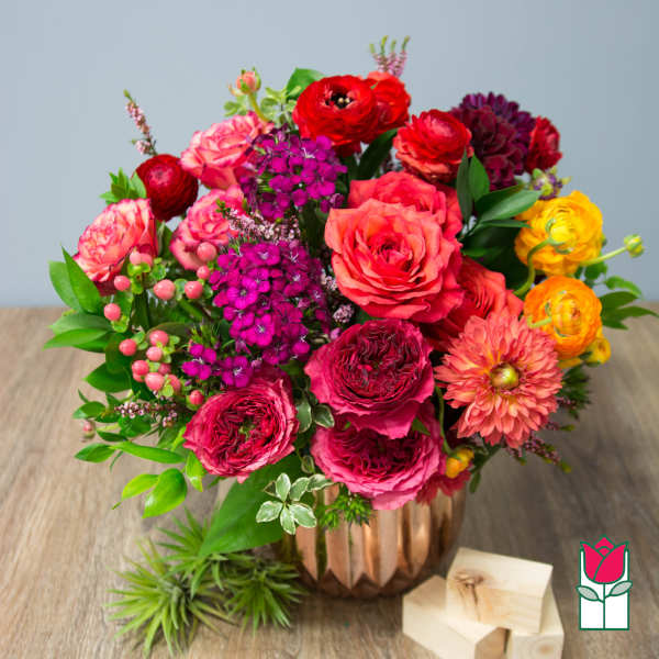 Mixed bouquet of pink, red, and yellow flowers in a copper vase