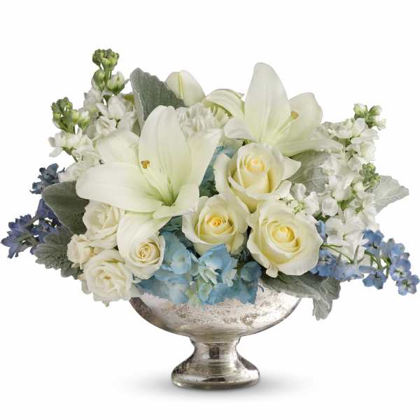 White roses and lilies in a silver pedestal vase with blue accents
