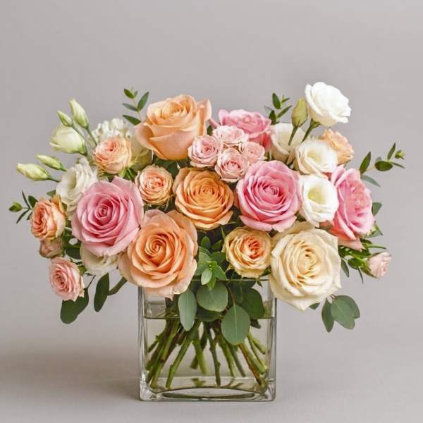 Bouquet of pink, peach, and white roses in a clear glass vase