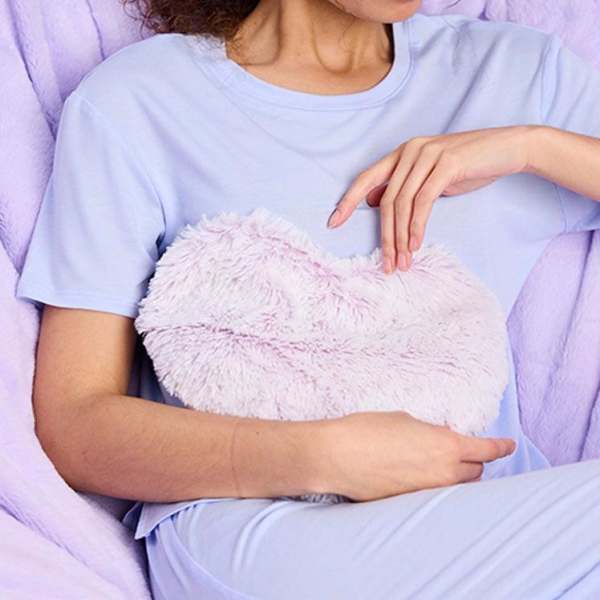 Person holding a fluffy heart-shaped plush pillow