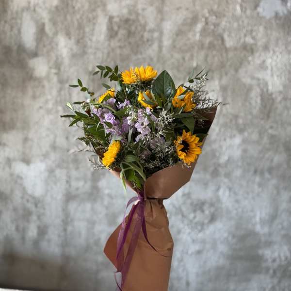 Bouquet of yellow sunflowers and lavender flowers wrapped in brown paper