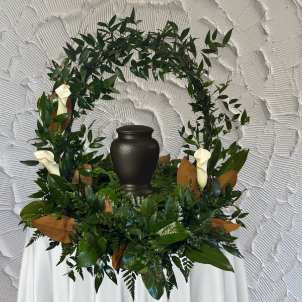 Green funeral wreath with white calla lilies around a black urn