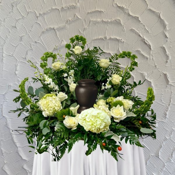 White floral funeral arrangement with a dark urn centerpiece