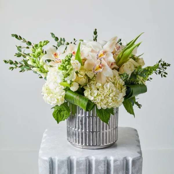 White and pale peach floral arrangement in a silver vase