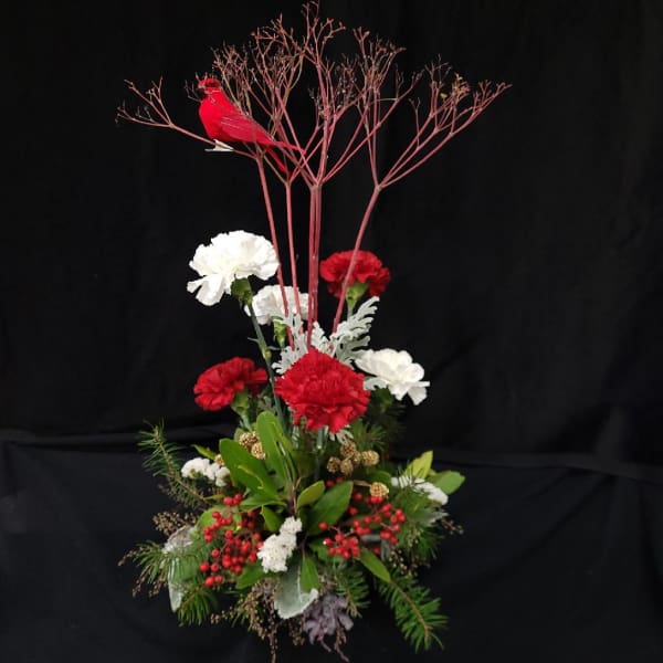 Tall red and white floral arrangement with a red bird topper
