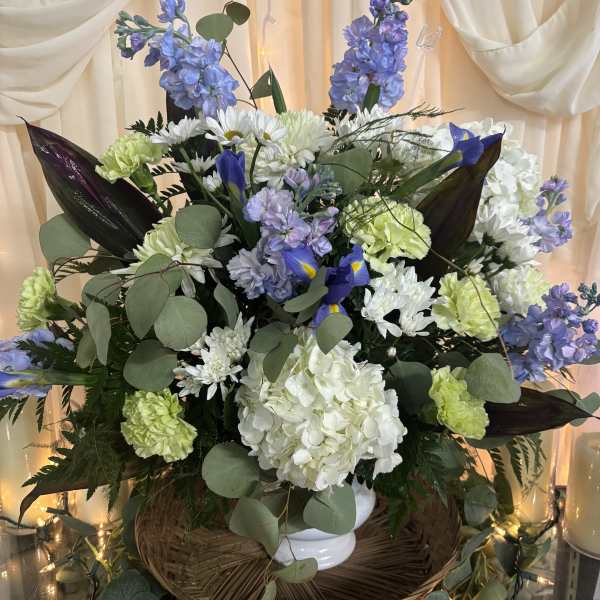 Large bouquet of white, blue, and green flowers in a white vase