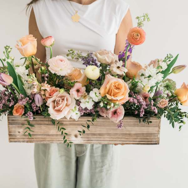 Mixed pastel flowers arranged in a wooden box
