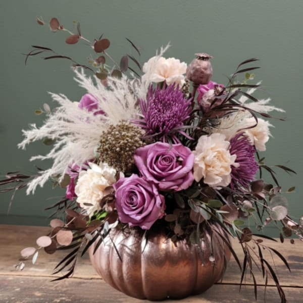 Purple and cream floral arrangement in a copper pumpkin vase
