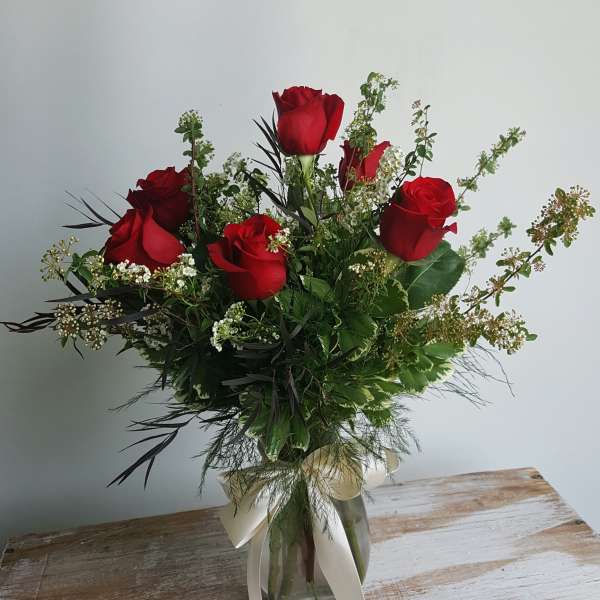Bouquet of red roses in a glass vase with white ribbon