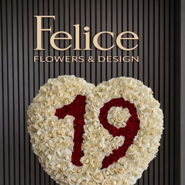 Heart-shaped rose arrangement on a stand with red lettering
