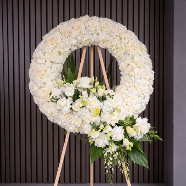 White floral wreath on a wooden easel with a cascading bouquet