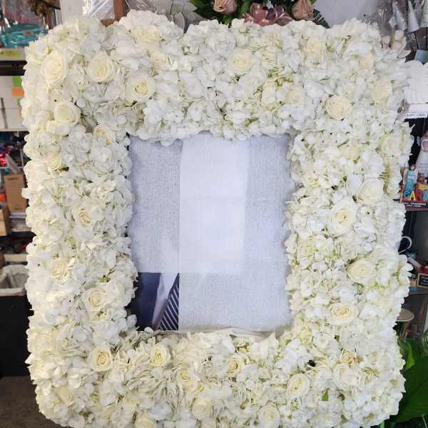 White floral standing frame with roses and hydrangeas on an easel