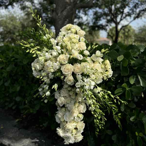 White floral cross-shaped arrangement with roses and orchids