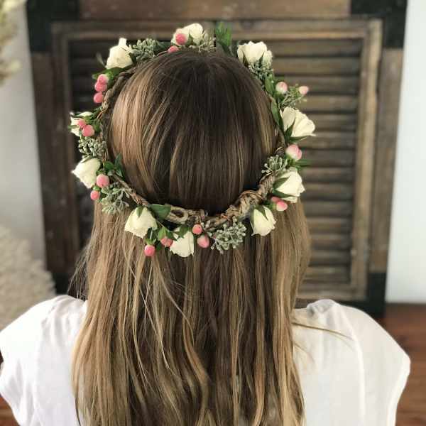 Floral crown with white blooms and pink berries worn on a person's head