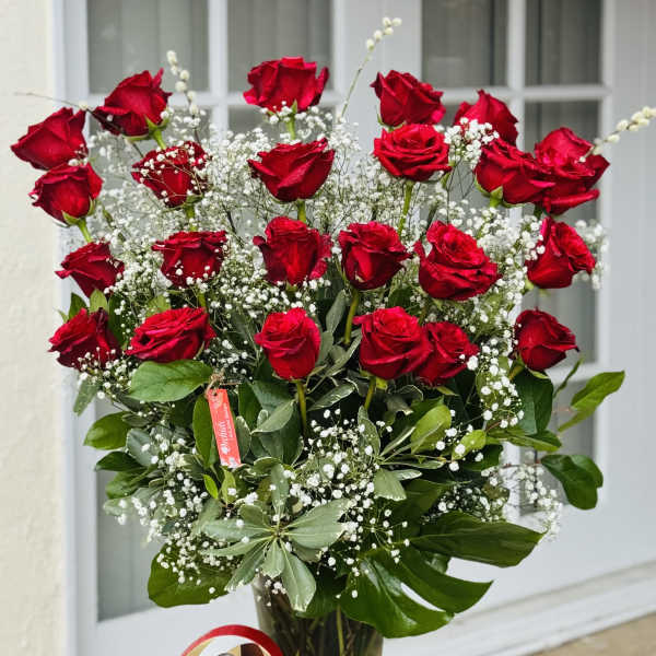 Bouquet of red roses in a glass vase with baby's breath and a heart-shaped chocolate box
