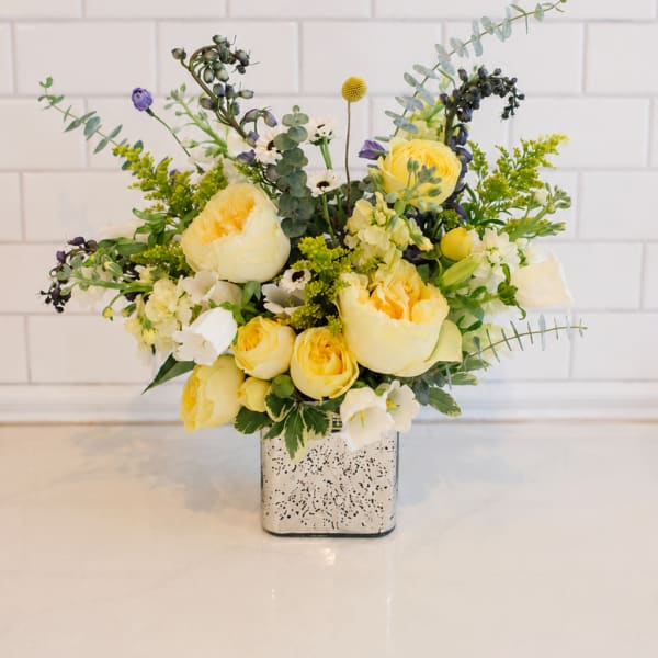 Yellow and white floral arrangement in a square silver vase