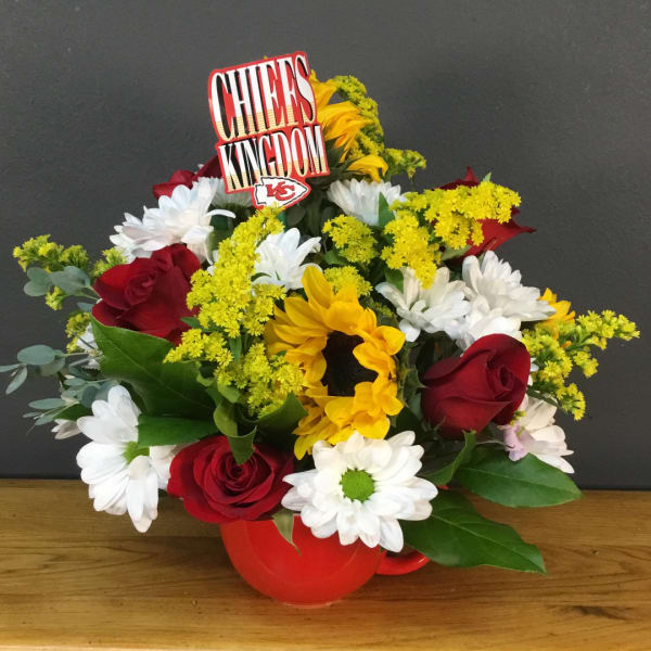Mixed bouquet of red roses, white daisies, and yellow sunflowers in a red mug