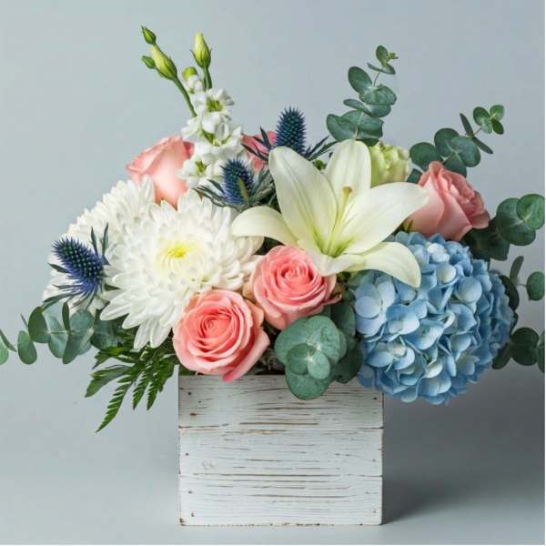 Mixed bouquet in a white wooden box with roses, lilies, hydrangea, and chrysanthemums