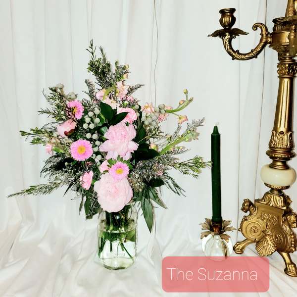Pink floral arrangement in a clear glass vase beside a green candle holder