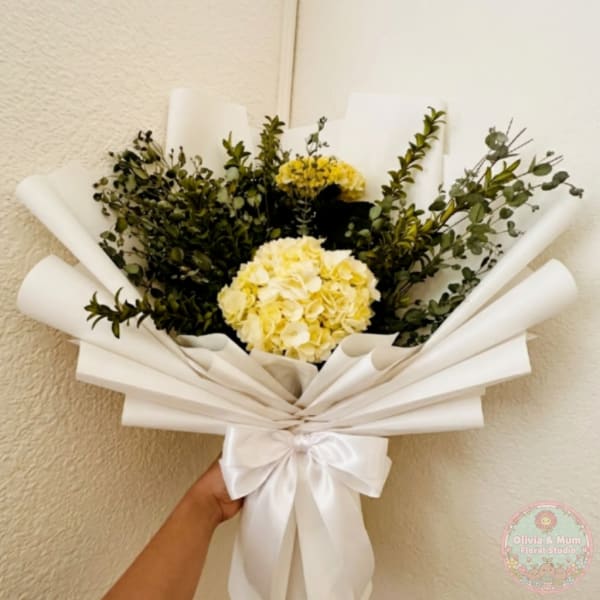 Bouquet of yellow hydrangeas and greenery wrapped in white paper