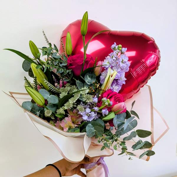 Bouquet of pink roses and lilies with a red heart balloon