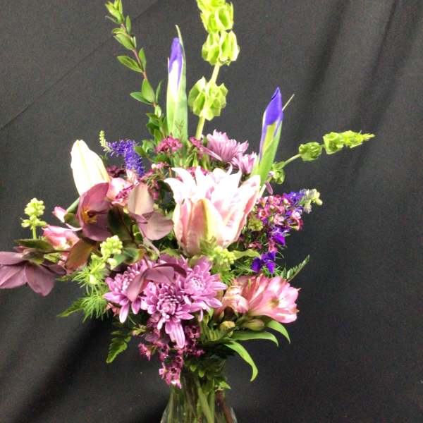 Mixed bouquet of pink, purple, and white flowers in a glass vase