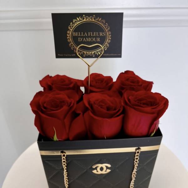 Six red roses in a black gift box with a gold chain and card topper