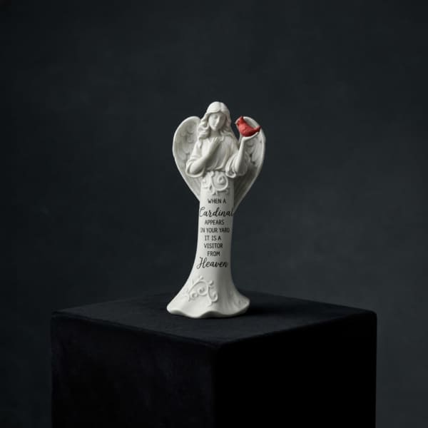 White angel figurine holding a red cardinal with memorial text