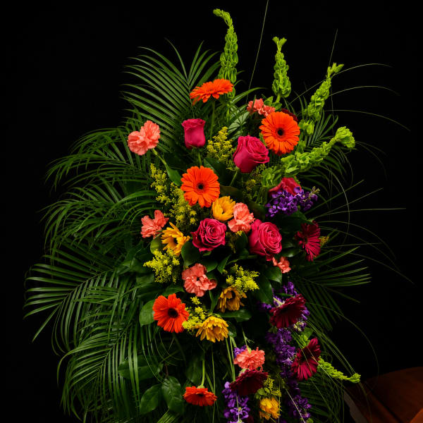 Tall standing floral spray with bright mixed blooms and palm fronds