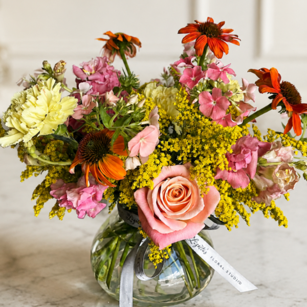 Mixed bouquet in a clear glass vase with pink, yellow, and orange flowers