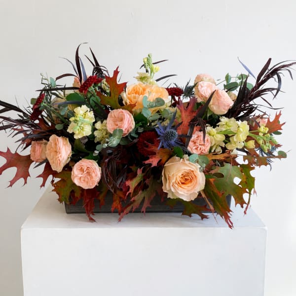 Peach roses and pale yellow flowers in a low rectangular container