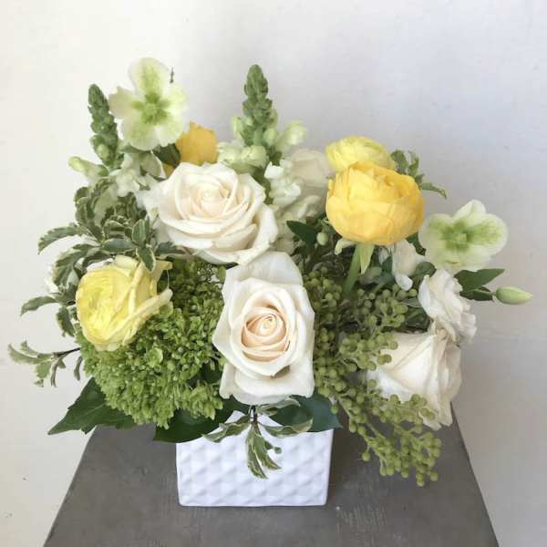 White and yellow rose arrangement in a white square vase