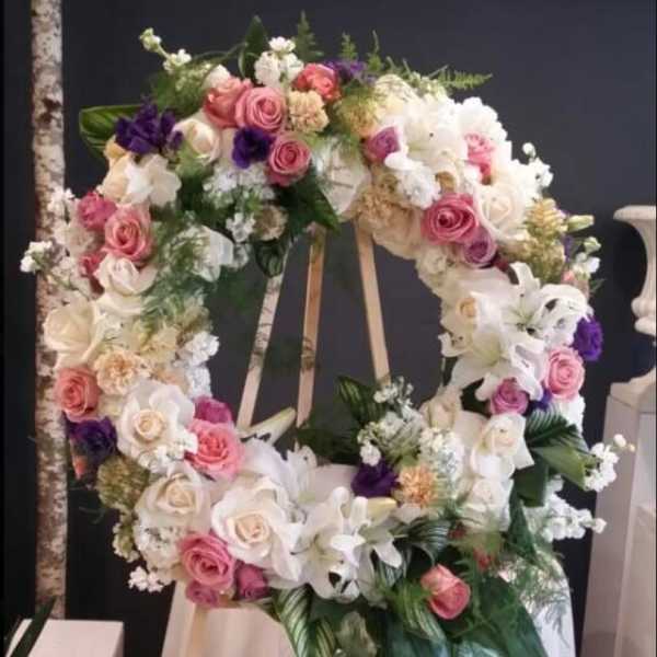 Large floral wreath on an easel with pink, white, and purple flowers