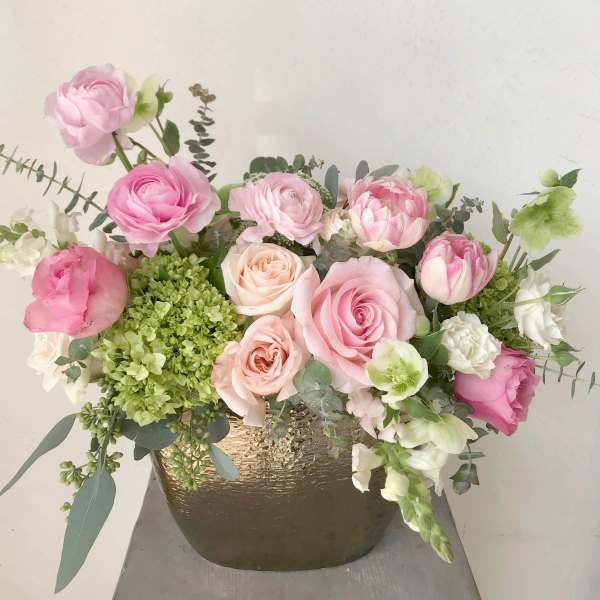 Pink and white roses arranged in a gold vase
